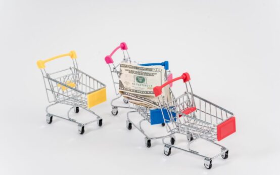 Colorful miniature shopping carts with dollar bills, symbolizing consumerism and finance.