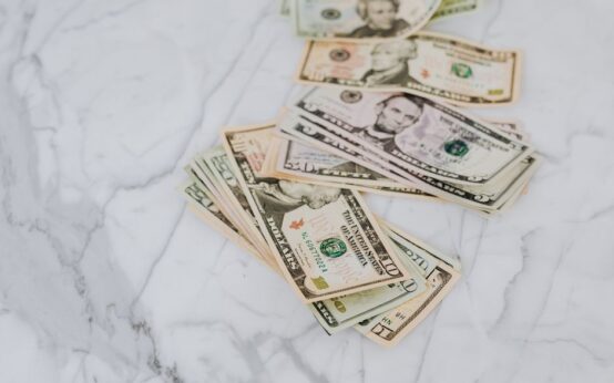 A stack of US dollar bills spread on a marble surface, representing wealth and finance.