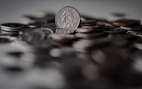 Pile of American coins with a focus on a quarter, symbolizing currency and wealth.